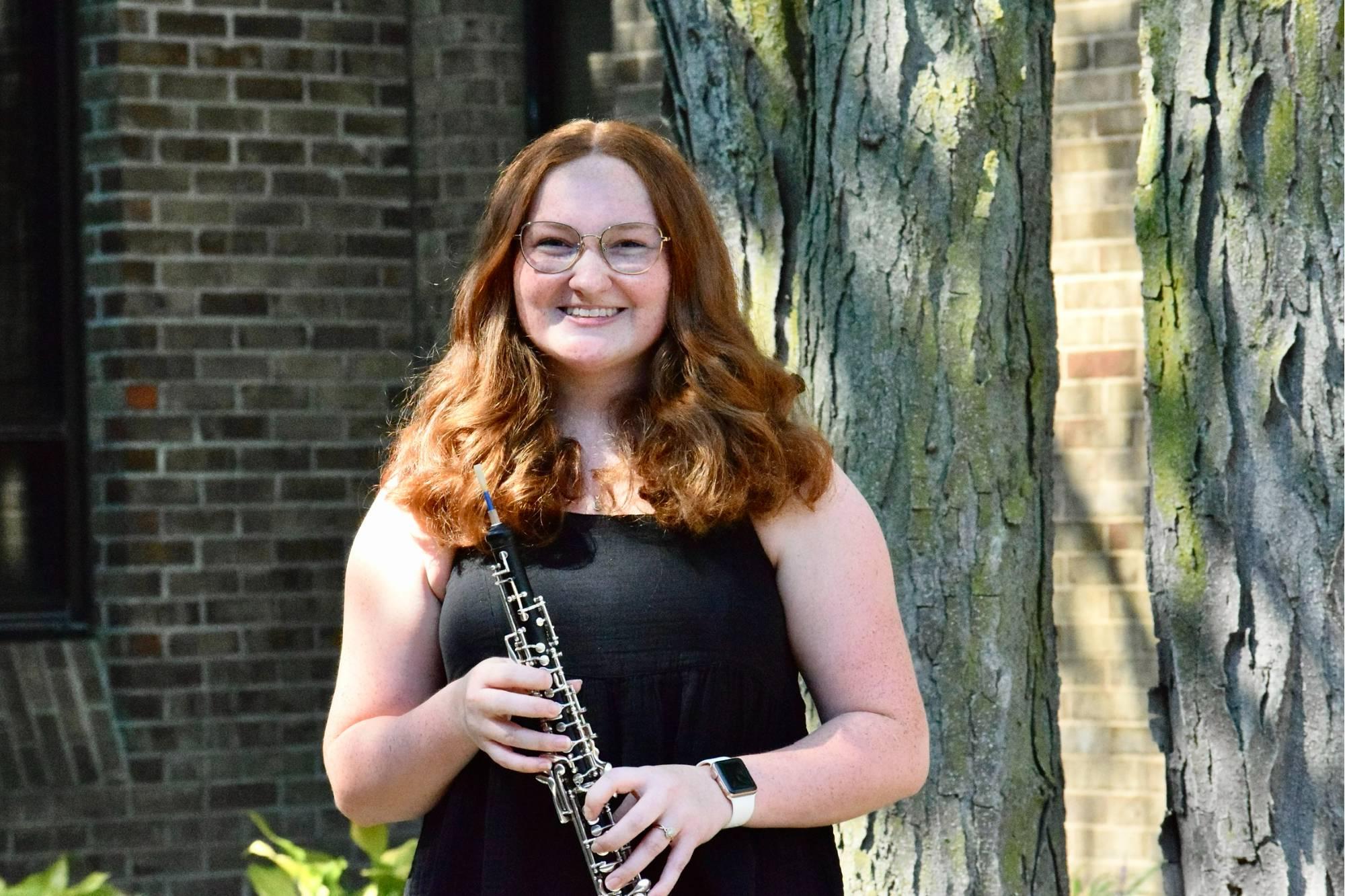 Natalie Kline standing outside and holding her oboe.